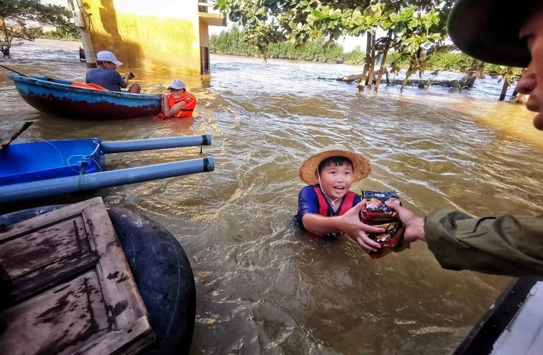 A boy gets food donation from a volunteer at a flooded area in Quang Binh province, Vietnam.  Thanh Dat/VNA via REUTERS
